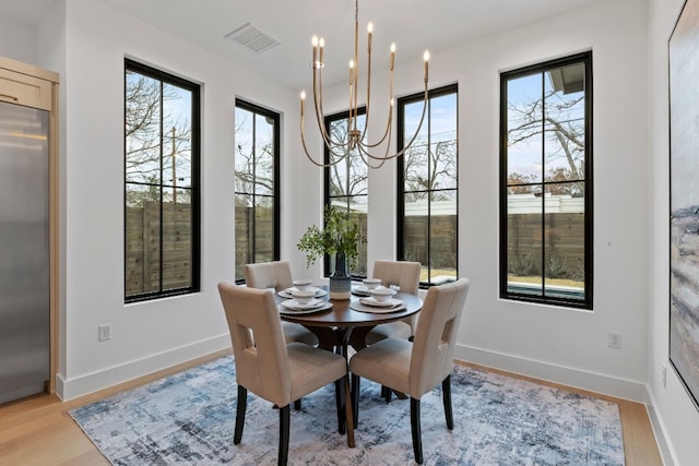 dining space featuring a wealth of natural light, visible vents, a notable chandelier, and light wood finished floors