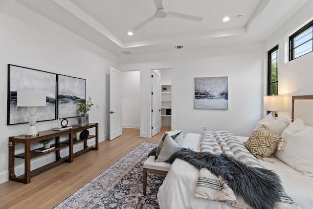 bedroom featuring light wood finished floors, visible vents, a tray ceiling, and recessed lighting