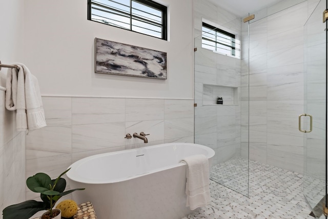 full bathroom with a soaking tub, a shower stall, and tile walls