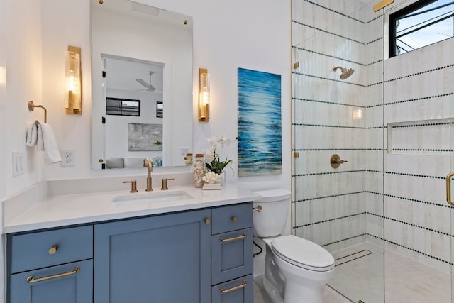 bathroom with toilet, ceiling fan, a tile shower, and vanity