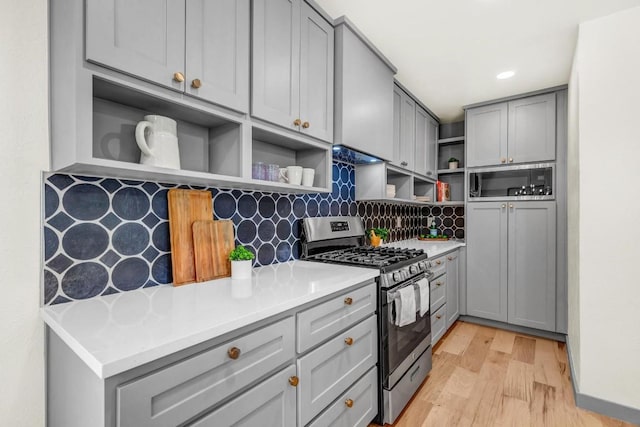 kitchen featuring stainless steel gas stove, open shelves, gray cabinets, and light countertops