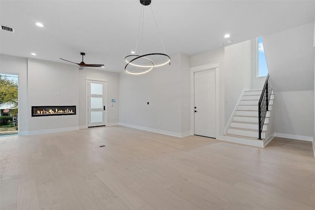 1135 Salina St, Austin, TX 78702 - unfurnished living room with healthy amount of natural light, a ceiling fan, stairs, a glass covered fireplace, and recessed lighting