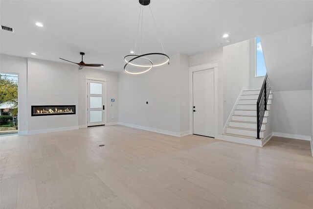 1135 Salina St, Austin, TX 78702 - unfurnished living room featuring plenty of natural light, ceiling fan, stairway, a glass covered fireplace, and recessed lighting