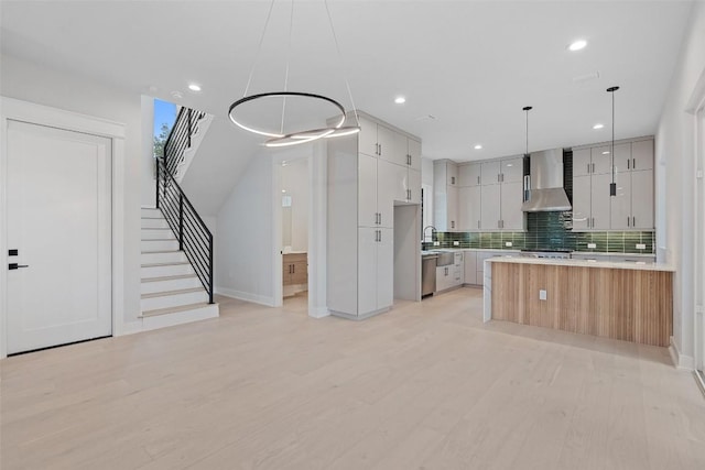1135 Salina St, Austin, TX 78702 - kitchen with wall chimney range hood, backsplash, light countertops, light wood-style floors, and recessed lighting