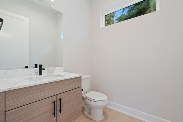 1135 Salina St, Austin, TX 78702 - bathroom featuring vanity, toilet, wood finished floors, and baseboards