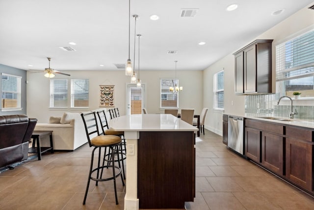 kitchen with visible vents, a center island, a breakfast bar area, stainless steel dishwasher, and a sink