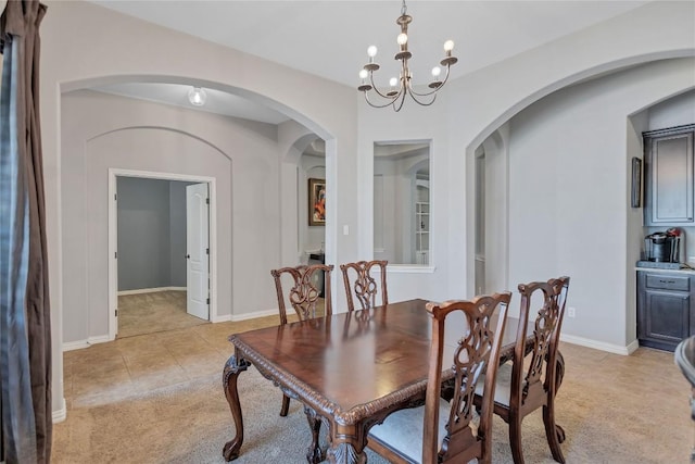 dining room featuring light tile patterned flooring, baseboards, a chandelier, and light colored carpet