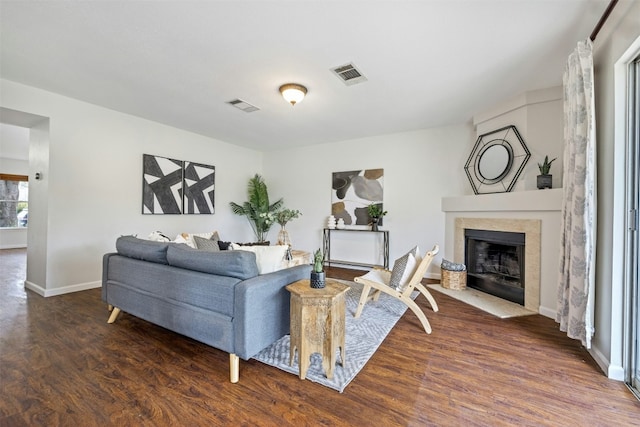 living area featuring dark wood-type flooring, visible vents, a fireplace, and baseboards