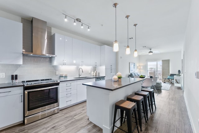 6444 Burnet Rd Unit 308, Austin, TX 78757 - kitchen with electric stove, dark countertops, wall chimney exhaust hood, light wood-style flooring, and a kitchen breakfast bar