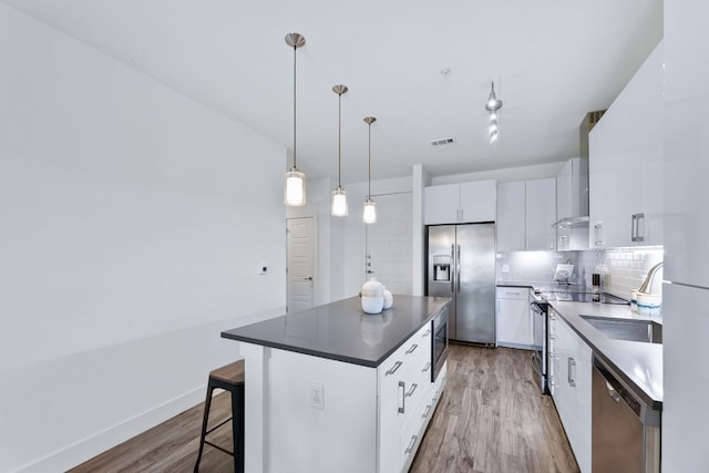 6444 Burnet Rd Unit 308, Austin, TX 78757 - kitchen featuring stainless steel appliances, light wood-type flooring, white cabinetry, a center island, and dark countertops