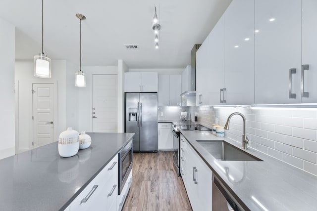 6444 Burnet Rd Unit 308, Austin, TX 78757 - kitchen with stainless steel appliances, tasteful backsplash, white cabinetry, light wood-type flooring, and dark countertops
