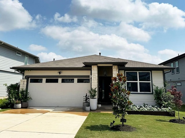 prairie-style house featuring an attached garage, driveway, a shingled roof, and a front yard