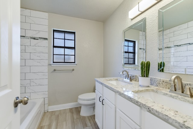 bathroom with toilet, baseboards, a sink, and wood finished floors