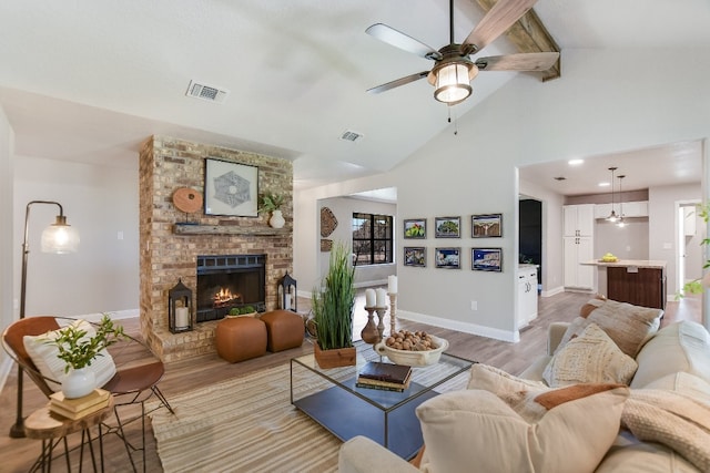 living room featuring a fireplace, visible vents, baseboards, beam ceiling, and light wood finished floors