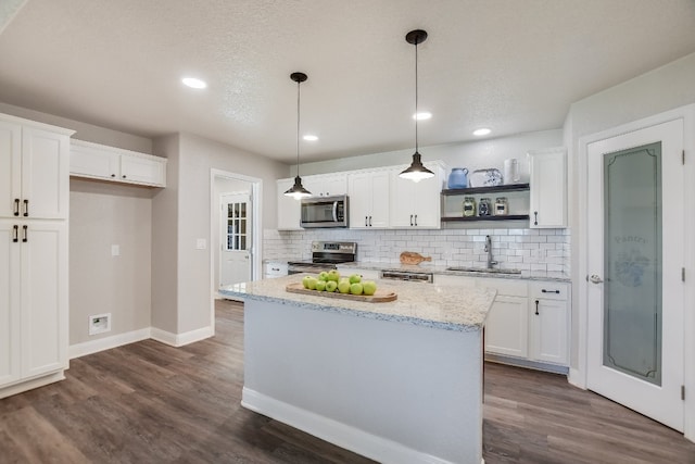 kitchen featuring pendant lighting, stainless steel appliances, a sink, and white cabinets