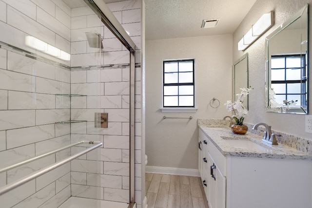 full bathroom featuring a stall shower, baseboards, visible vents, and a sink