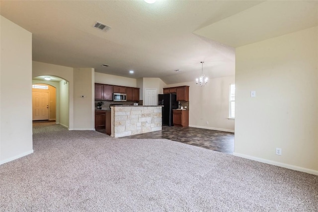 214 Teron Dr, San Marcos, TX 78666 - unfurnished living room featuring dark carpet, arched walkways, visible vents, baseboards, and a notable chandelier