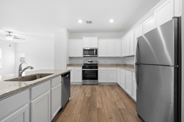 kitchen featuring light stone counters, a sink, visible vents, white cabinetry, and appliances with stainless steel finishes