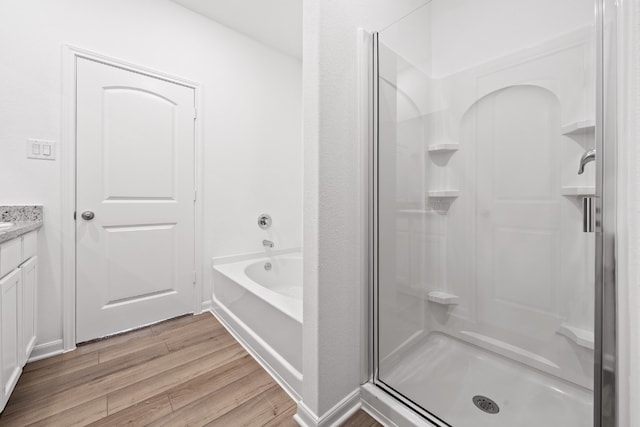 full bath with a stall shower, a garden tub, wood finished floors, and vanity