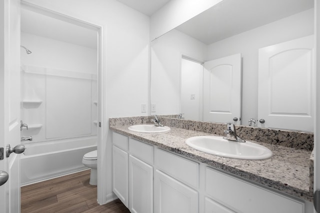 bathroom with double vanity, wood finished floors, a sink, and toilet