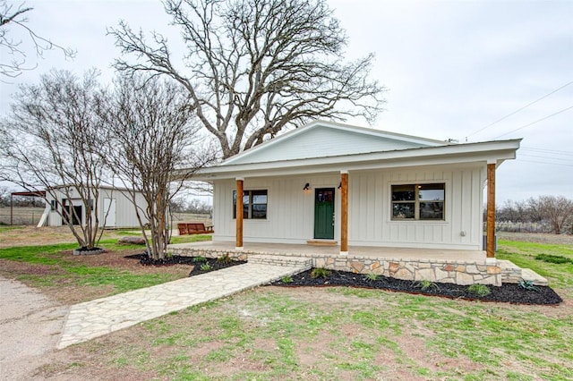 view of front facade with covered porch, board and batten siding, and a front yard