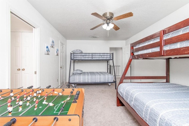 carpeted bedroom featuring visible vents, ceiling fan, and a textured ceiling