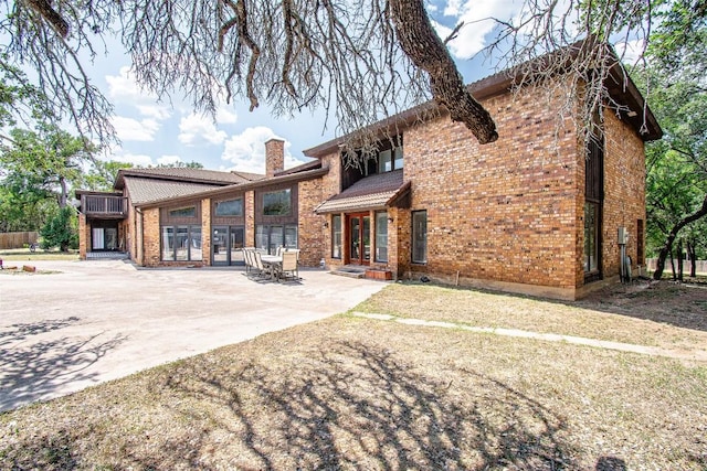 view of front of property with a patio, brick siding, and a chimney