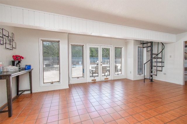 living area with tile patterned flooring, stairs, and french doors