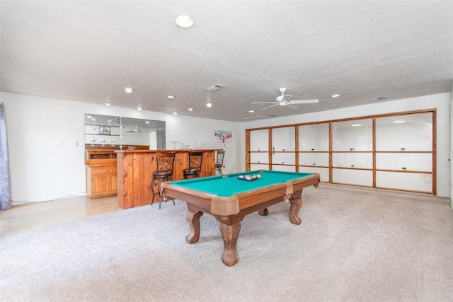 recreation room with light colored carpet, pool table, indoor bar, and a textured ceiling