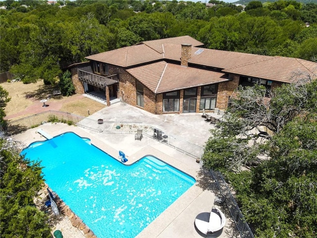 view of swimming pool featuring a patio, fence, a fenced in pool, and a view of trees