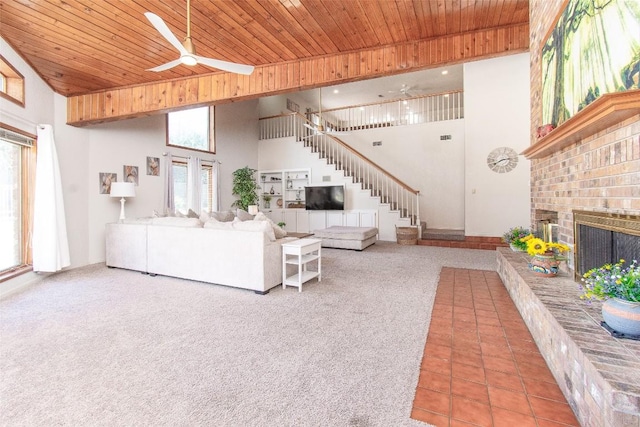 tiled living room featuring wood ceiling, a fireplace, high vaulted ceiling, and stairs