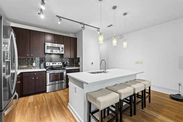 1900 Barton Springs Rd Unit 4040, Austin, TX 78704 - kitchen featuring appliances with stainless steel finishes, light wood-style floors, backsplash, and dark brown cabinets