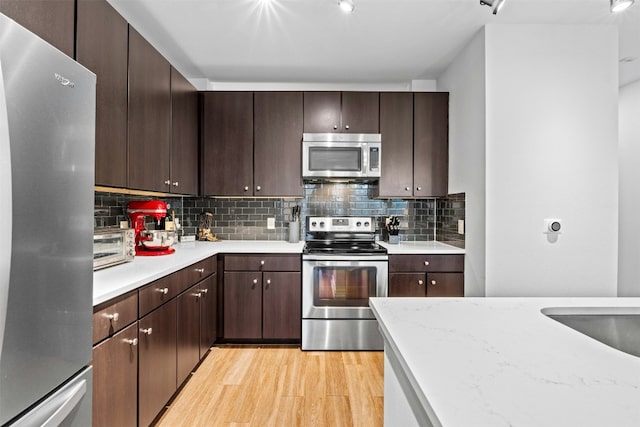 1900 Barton Springs Rd Unit 4040, Austin, TX 78704 - kitchen with stainless steel appliances, light wood-type flooring, backsplash, and dark brown cabinets