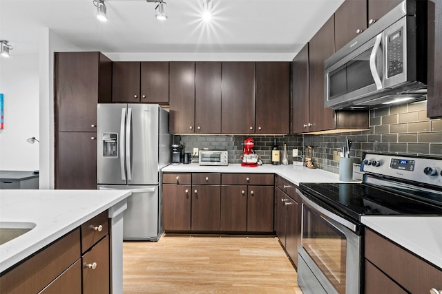 1900 Barton Springs Rd Unit 4040, Austin, TX 78704 - kitchen featuring appliances with stainless steel finishes, light countertops, light wood finished floors, backsplash, and dark brown cabinetry