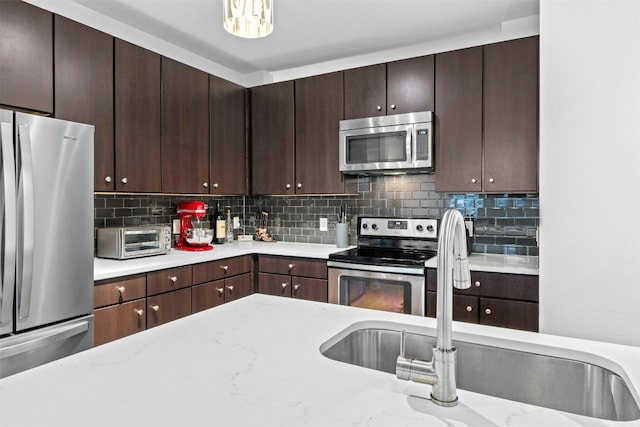 1900 Barton Springs Rd Unit 4040, Austin, TX 78704 - kitchen featuring appliances with stainless steel finishes, dark brown cabinetry, and tasteful backsplash