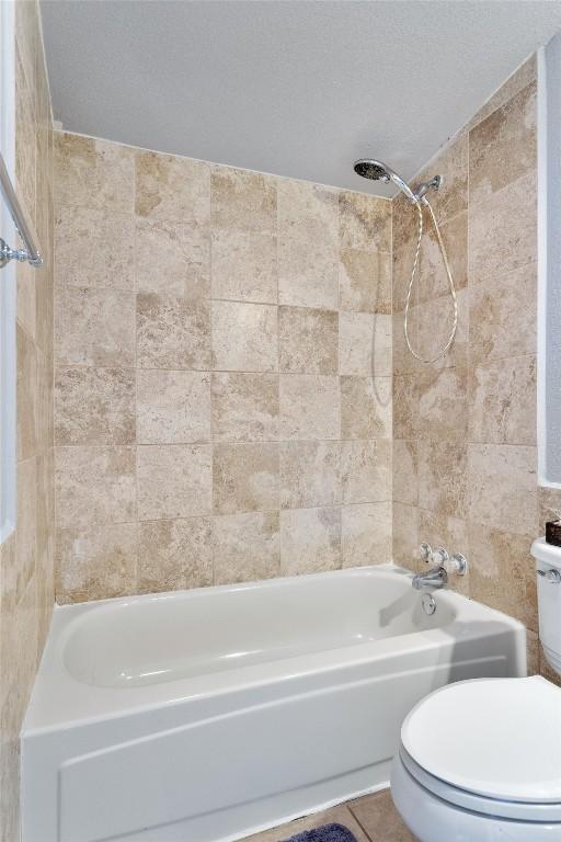 full bath with shower / washtub combination, tile patterned flooring, a textured ceiling, and toilet