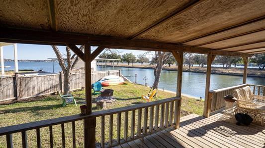 wooden terrace with a water view, a yard, and fence