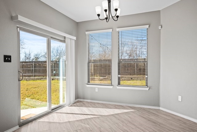 interior space with a notable chandelier, baseboards, and light wood-style floors