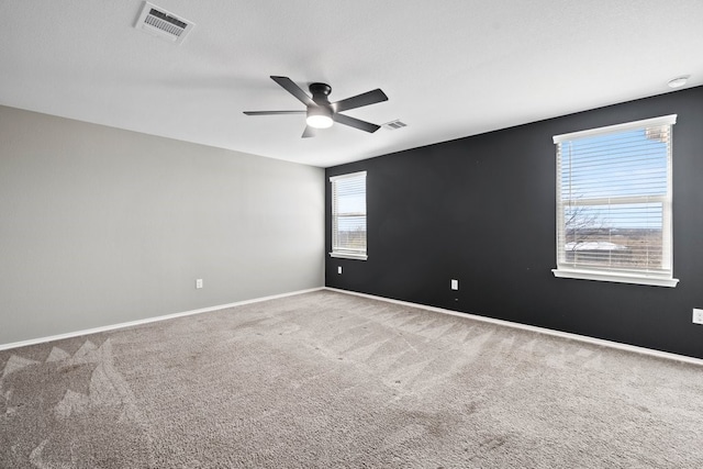 empty room featuring carpet floors, visible vents, and baseboards