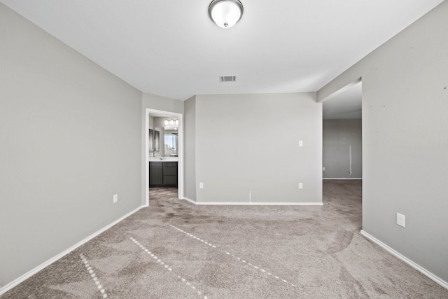 empty room with carpet, visible vents, and baseboards