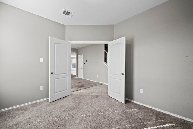 unfurnished bedroom with carpet flooring, visible vents, and baseboards