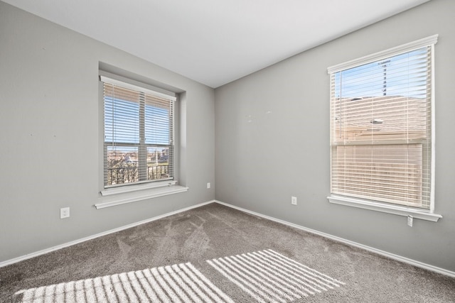 carpeted empty room featuring baseboards