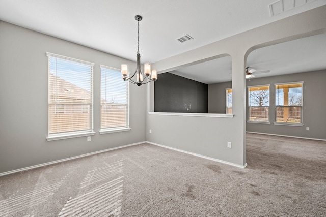 carpeted spare room with baseboards, visible vents, and ceiling fan with notable chandelier