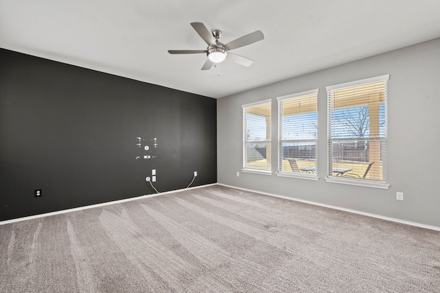 empty room featuring ceiling fan, baseboards, and carpet flooring