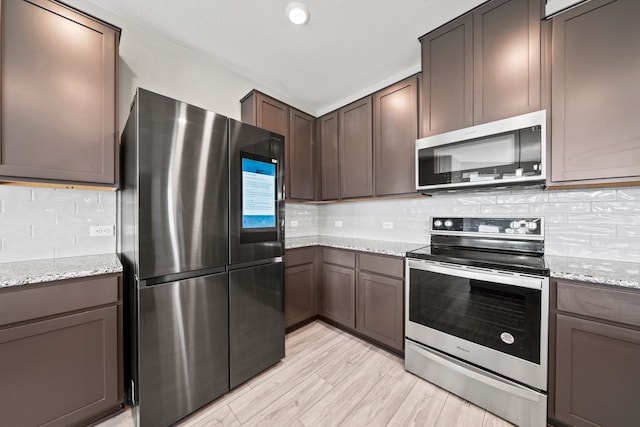 kitchen featuring stainless steel appliances, tasteful backsplash, light stone counters, and dark brown cabinetry