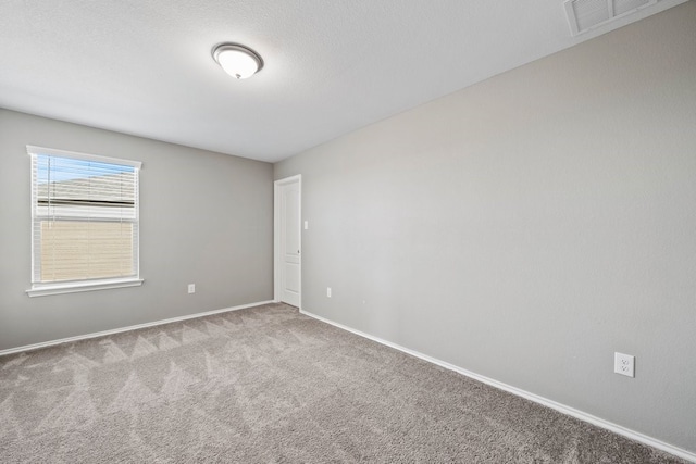 spare room with baseboards, a textured ceiling, visible vents, and light colored carpet