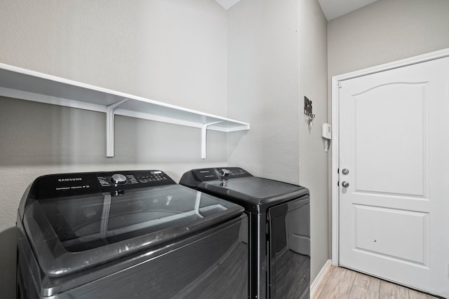 laundry area featuring light wood-style flooring, laundry area, washer and clothes dryer, and baseboards