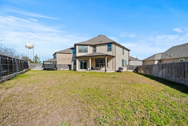 back of property with a yard, a fenced backyard, a patio, and a trampoline