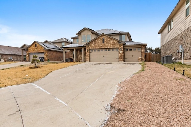 traditional home featuring an attached garage, central AC, brick siding, driveway, and roof mounted solar panels