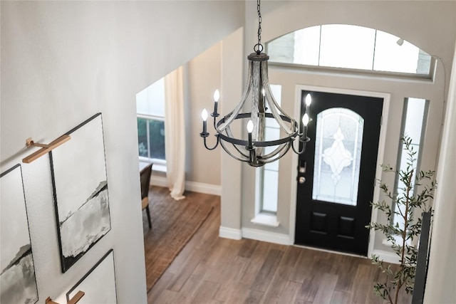 entrance foyer with baseboards, a high ceiling, wood finished floors, and an inviting chandelier